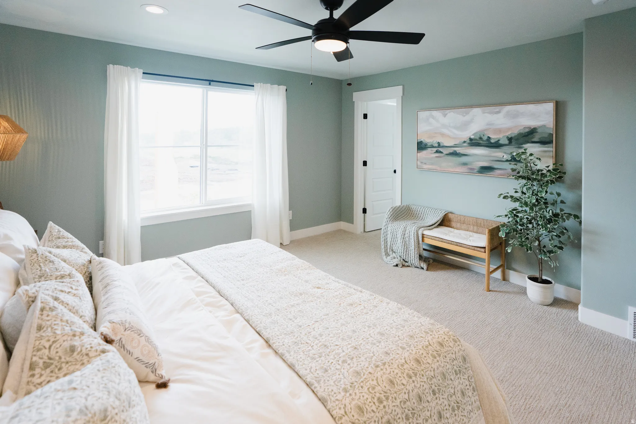 Carpeted bedroom with a large window, a black ceiling fan with integrated lighting, recessed lighting, and a white paneled door with black hardware