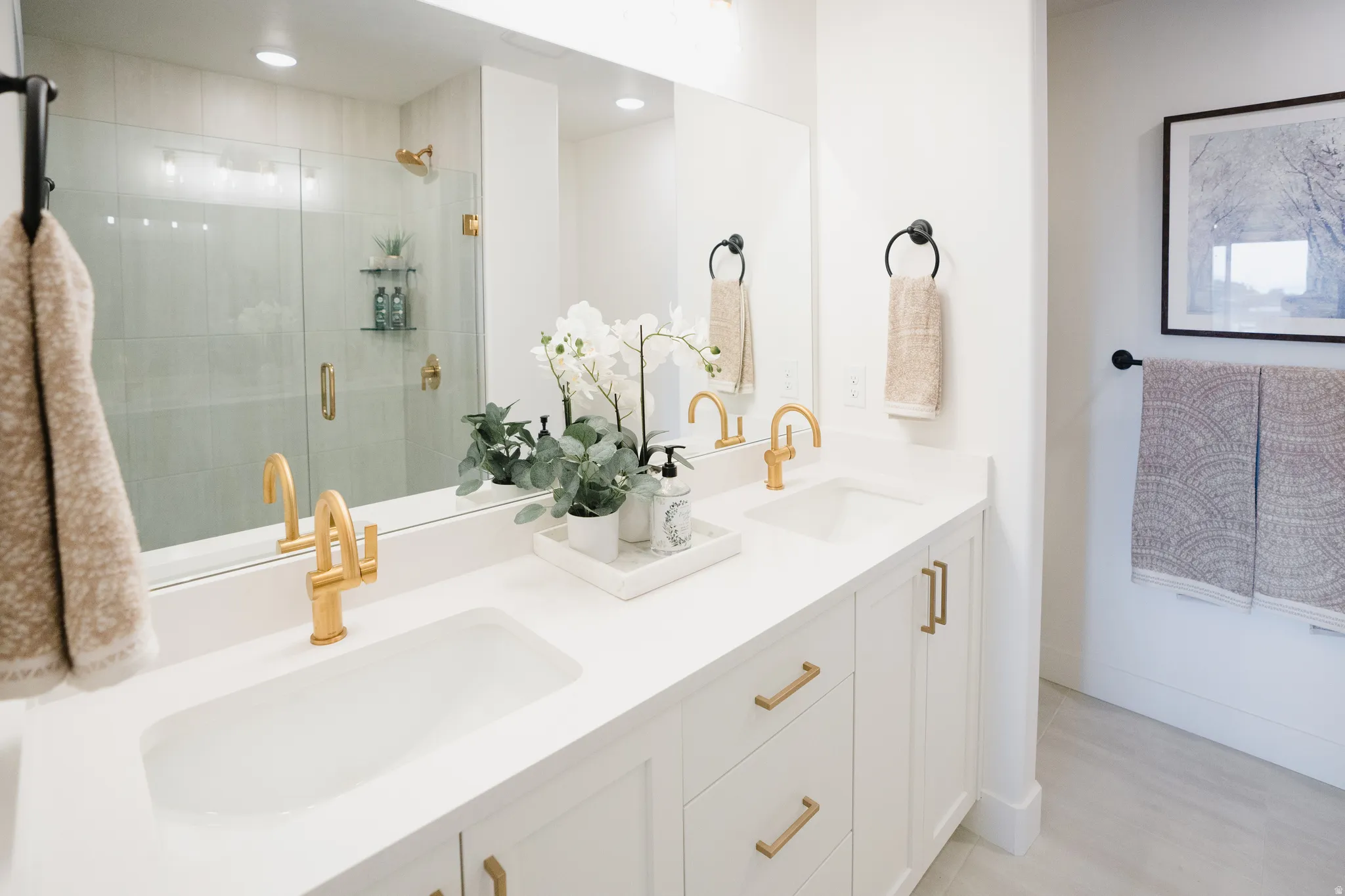 Dual vanity featuring white countertops, undermount sinks, and gold-finish faucets
