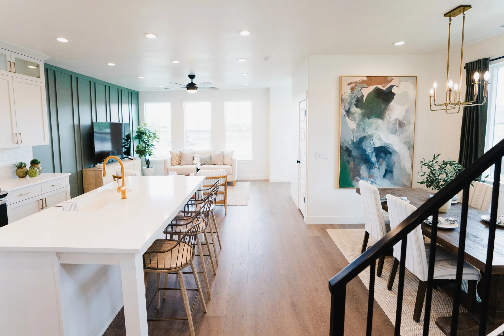 Open-concept living space featuring wood-finish flooring, a kitchen island with seating, recessed lighting, and a board and batten accent wall