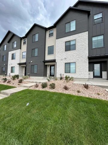 Contemporary townhome exterior featuring white brick, dark gray siding, and black-framed windows