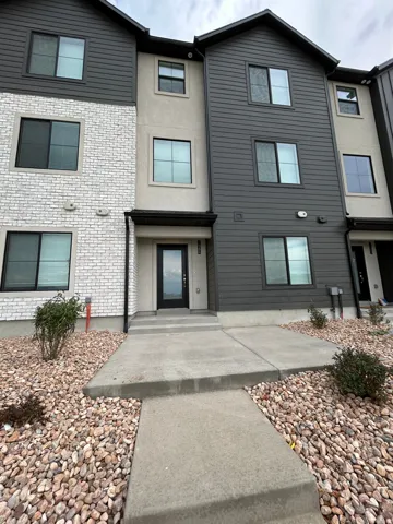 Contemporary facade featuring dark horizontal siding, white brick, and light stucco finishes