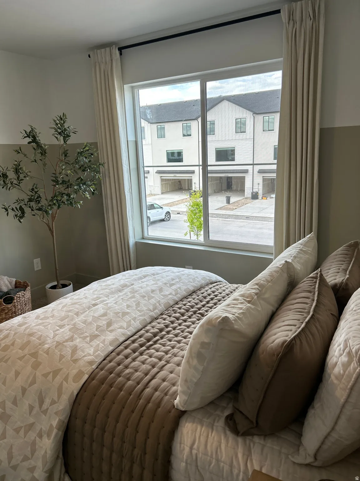 Bright bedroom featuring a large window with privacy blinds, light wall tones, and a dark curtain rod