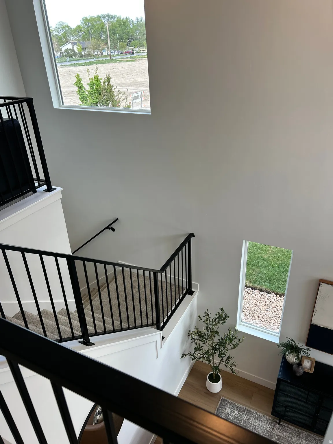 Open staircase featuring black metal railings and neutral carpeting