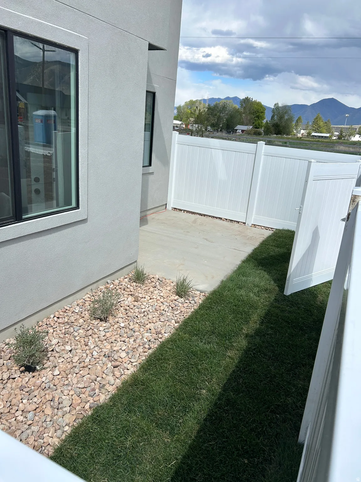 Private side yard featuring a concrete patio, a section of manicured lawn, and a gravel bed with low-maintenance plantings