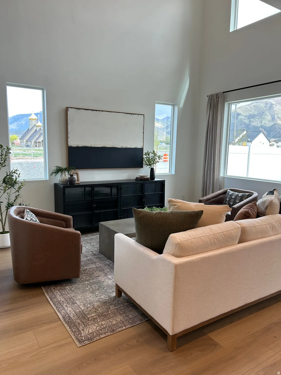 Living area with high ceilings, multiple windows, and wood-finish flooring