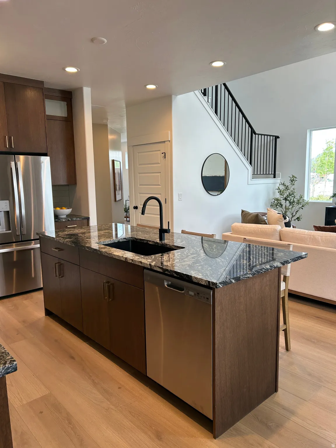 Kitchen island featuring a black sink with a matte black faucet, granite countertops, and integrated stainless steel dishwasher