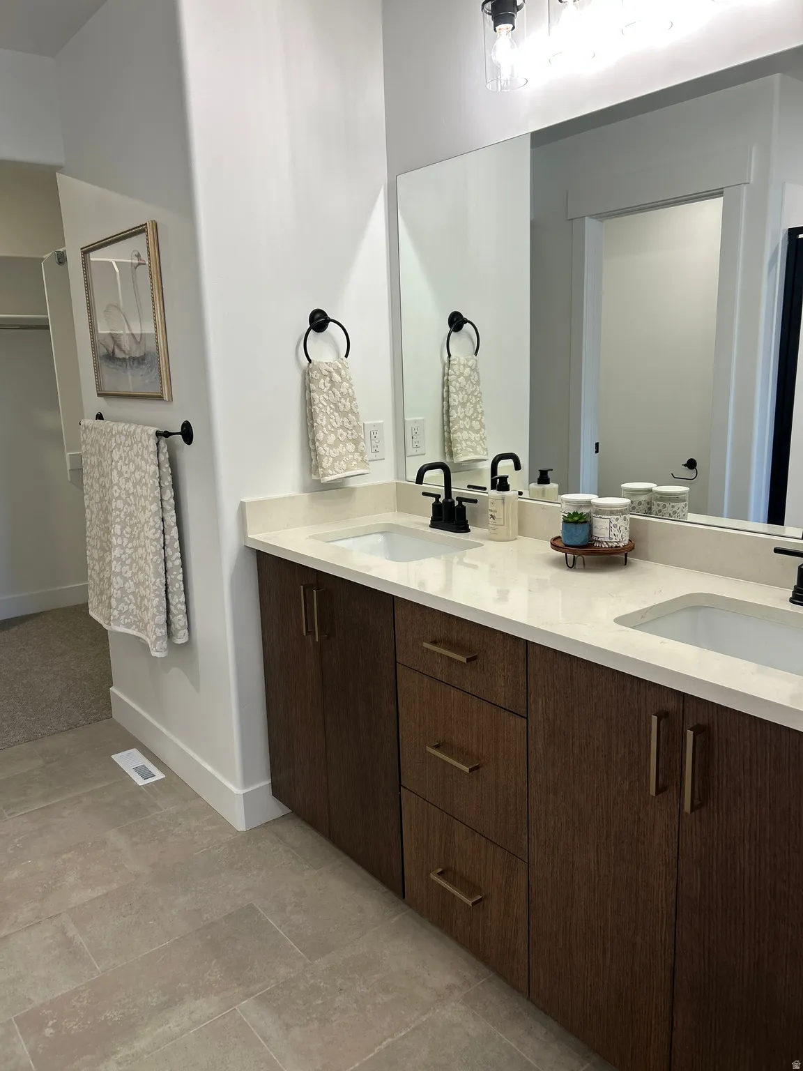 Dual sink vanity with dark wood-finish cabinetry and light-toned countertops