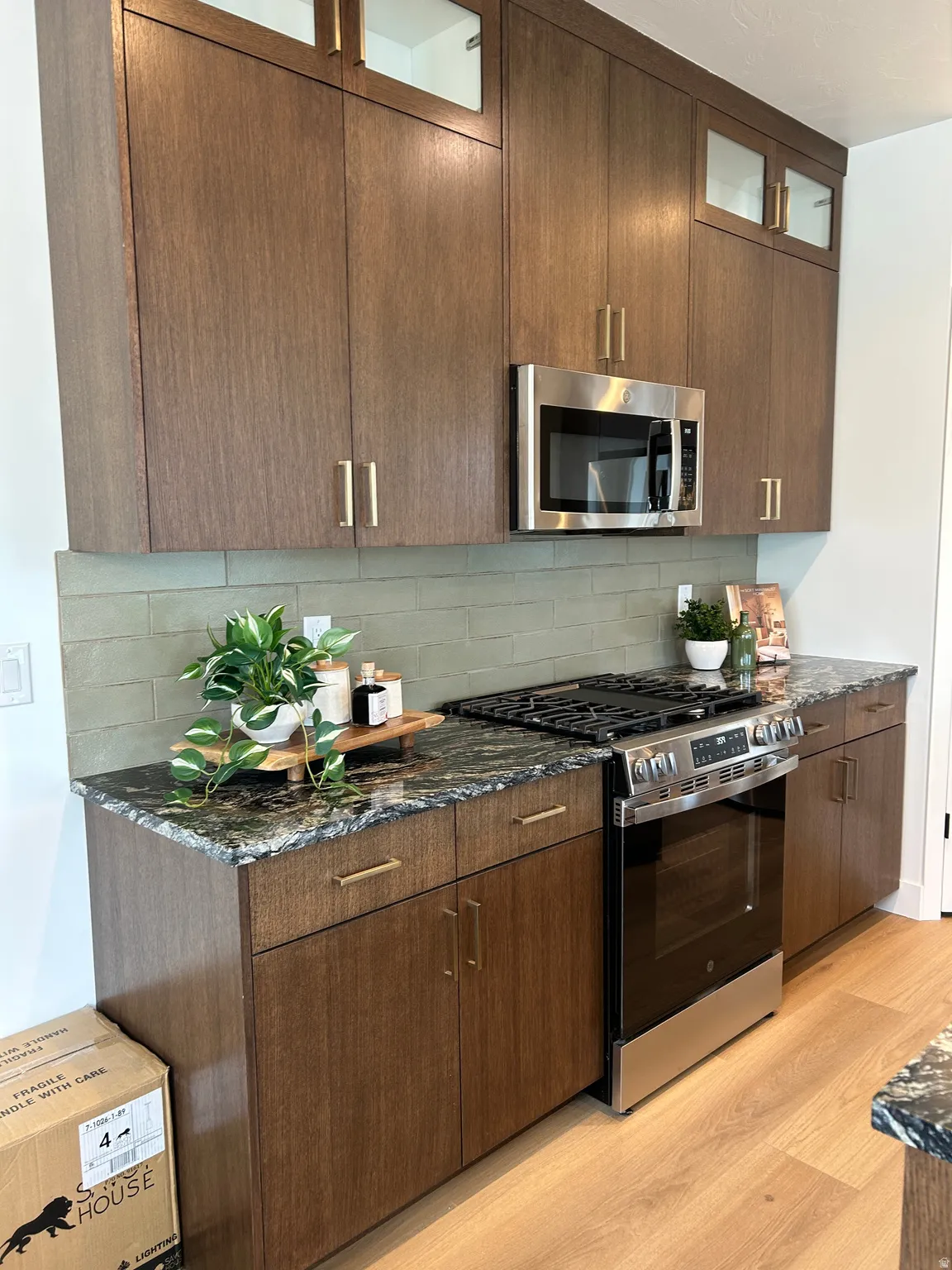 Kitchen featuring dark wood-finish cabinetry with gold-tone hardware, stainless steel appliances, a range with a griddle, and a patterned stone countertop