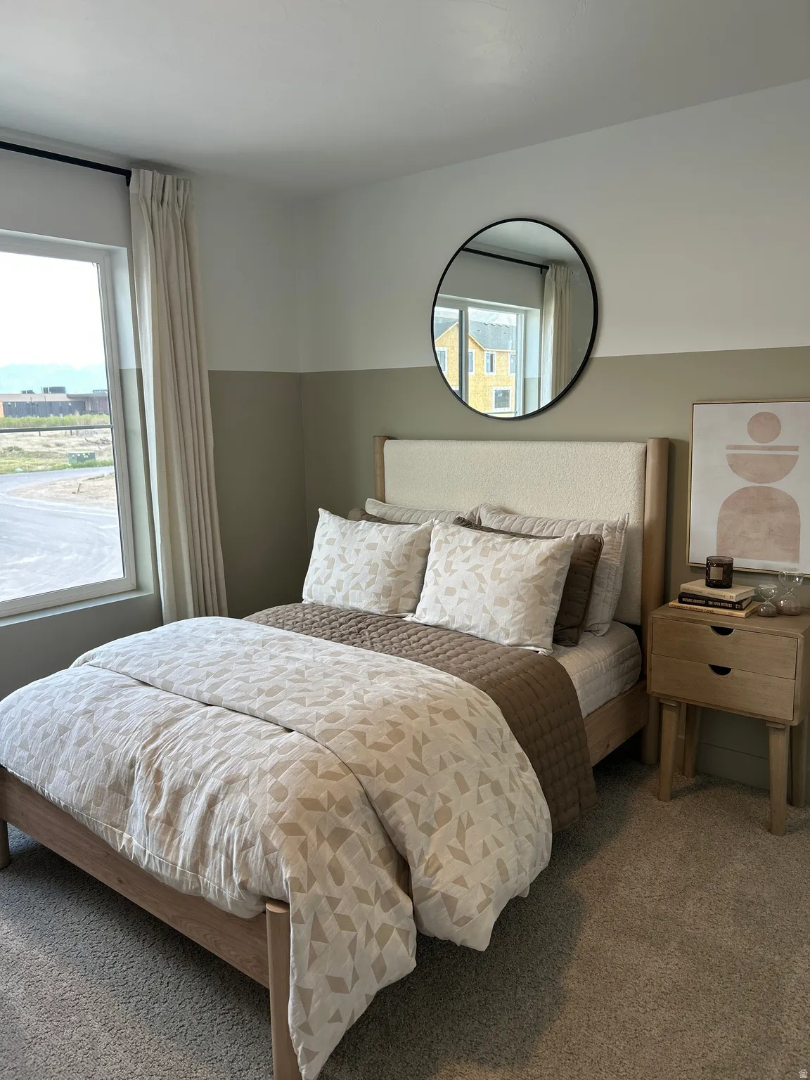 Bedroom featuring neutral-toned walls, a large window with drapes, and soft carpeting