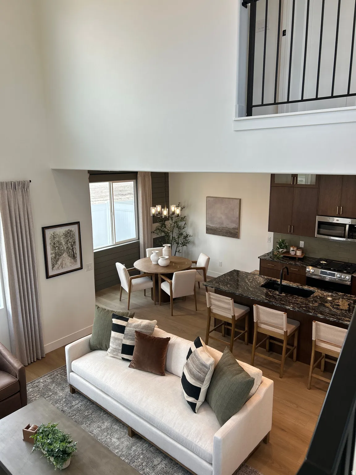 Open concept living space featuring a two-story ceiling, wood-finish flooring, and a kitchen island with seating