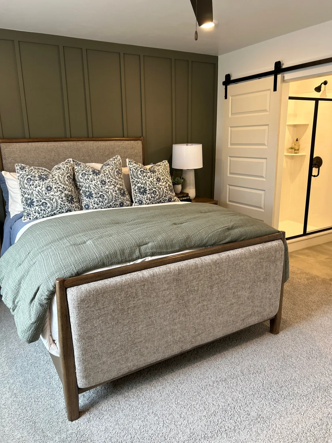 Bedroom featuring a board and batten accent wall, light gray carpet, and a modern barn door