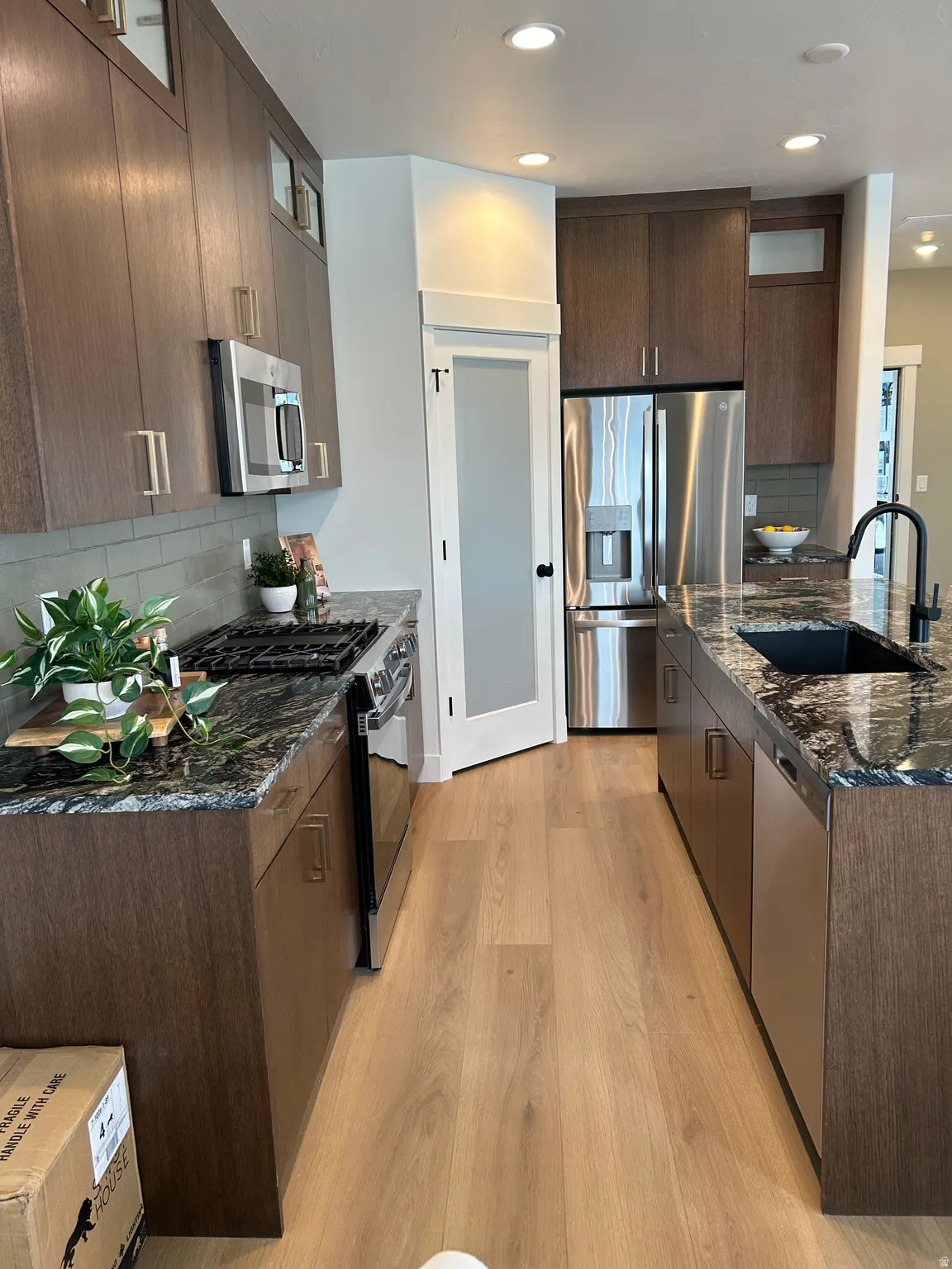 Kitchen featuring wood-finish cabinetry, dark stone countertops, and light wood-finish flooring