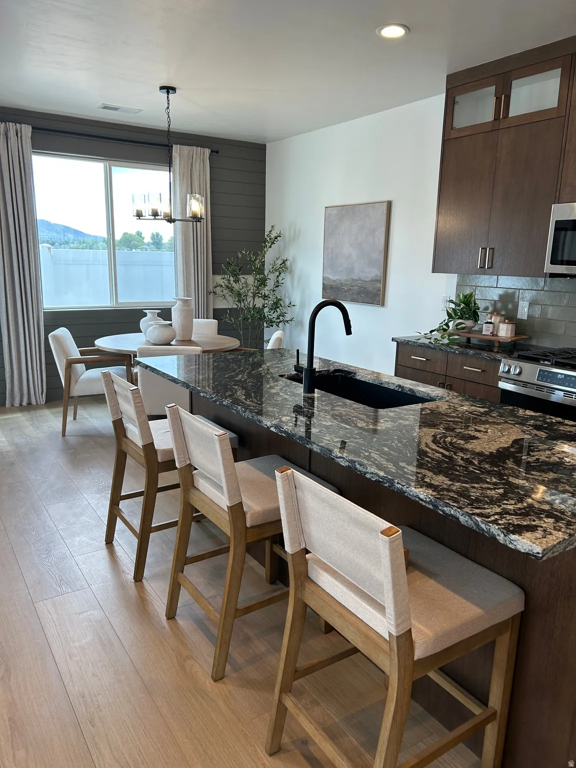Kitchen featuring a dark granite countertop with an undermount sink, dark wood cabinetry, and stainless steel appliances