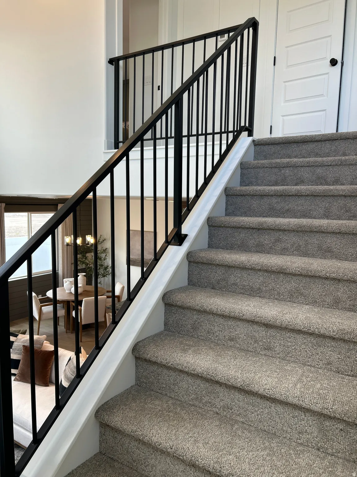 Carpeted staircase with black iron balusters and railing