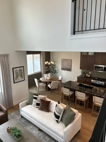 Open concept living space featuring a two-story ceiling, wood-finish flooring, and a kitchen island with seating