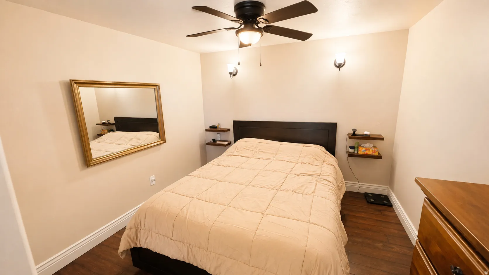 ADU #1 - Bedroom featuring wood-finish flooring, a ceiling fan with integrated lighting, and two wall-mounted sconces
