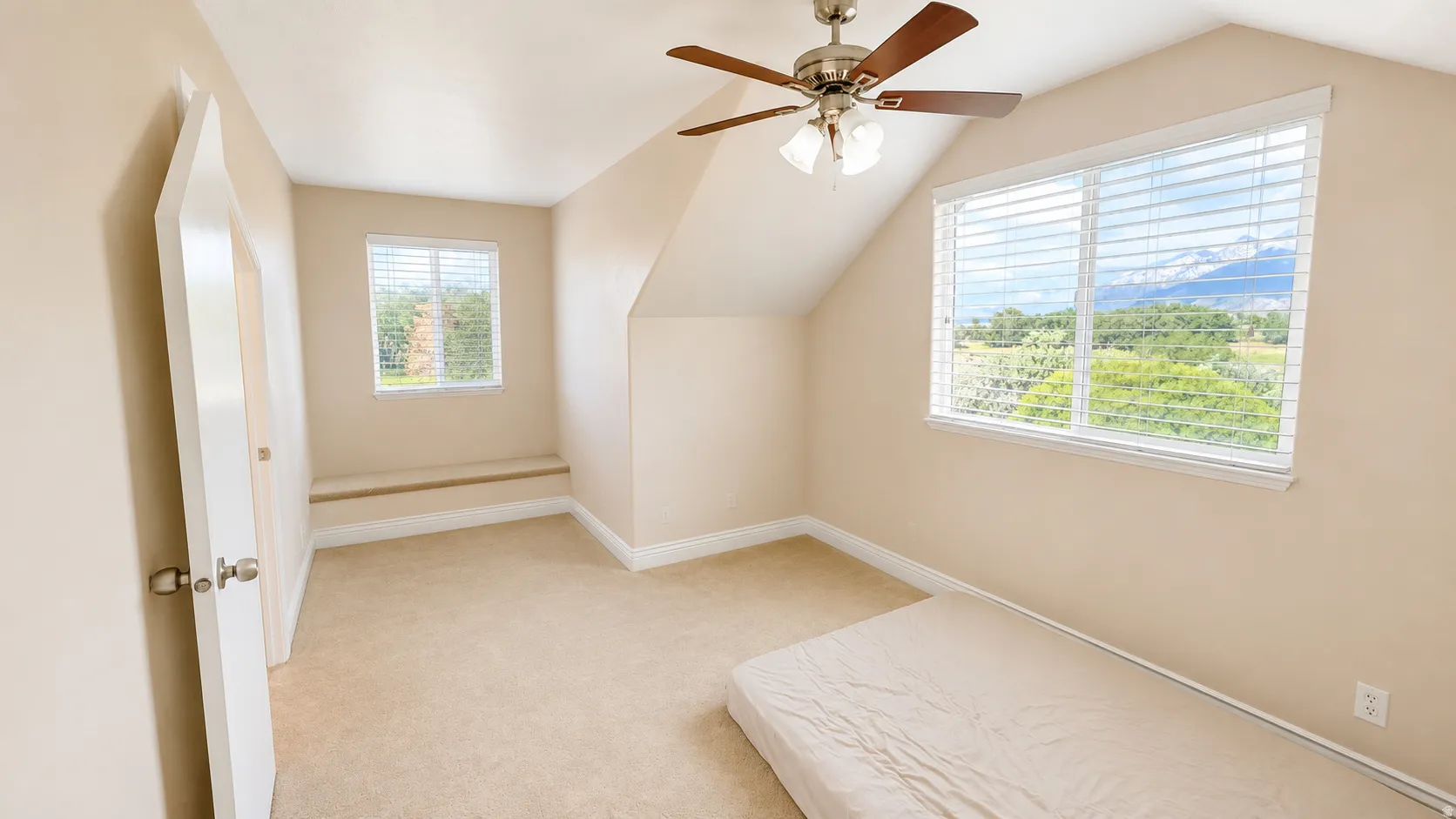 ADU #2 - Carpeted room with a ceiling fan light fixture, two windows, and a built-in window seat