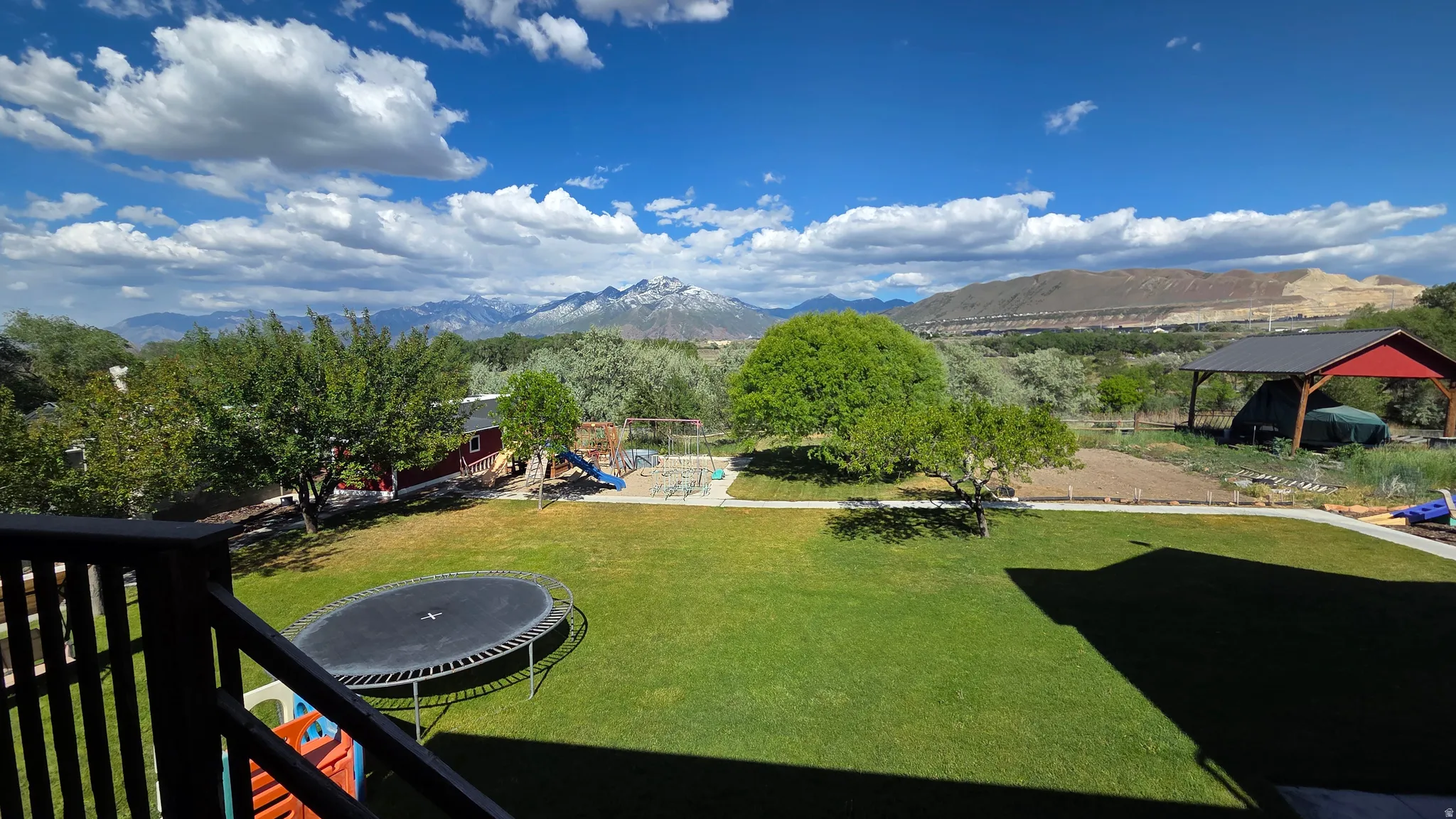 Expansive green lawn with mature trees and a distant mountain backdrop
