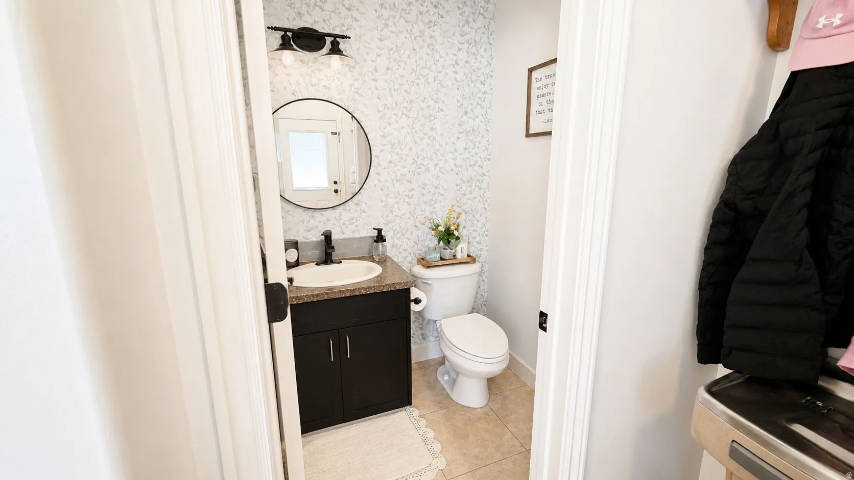 Powder room featuring a single vanity with a dark cabinet, speckled countertop, and black faucet