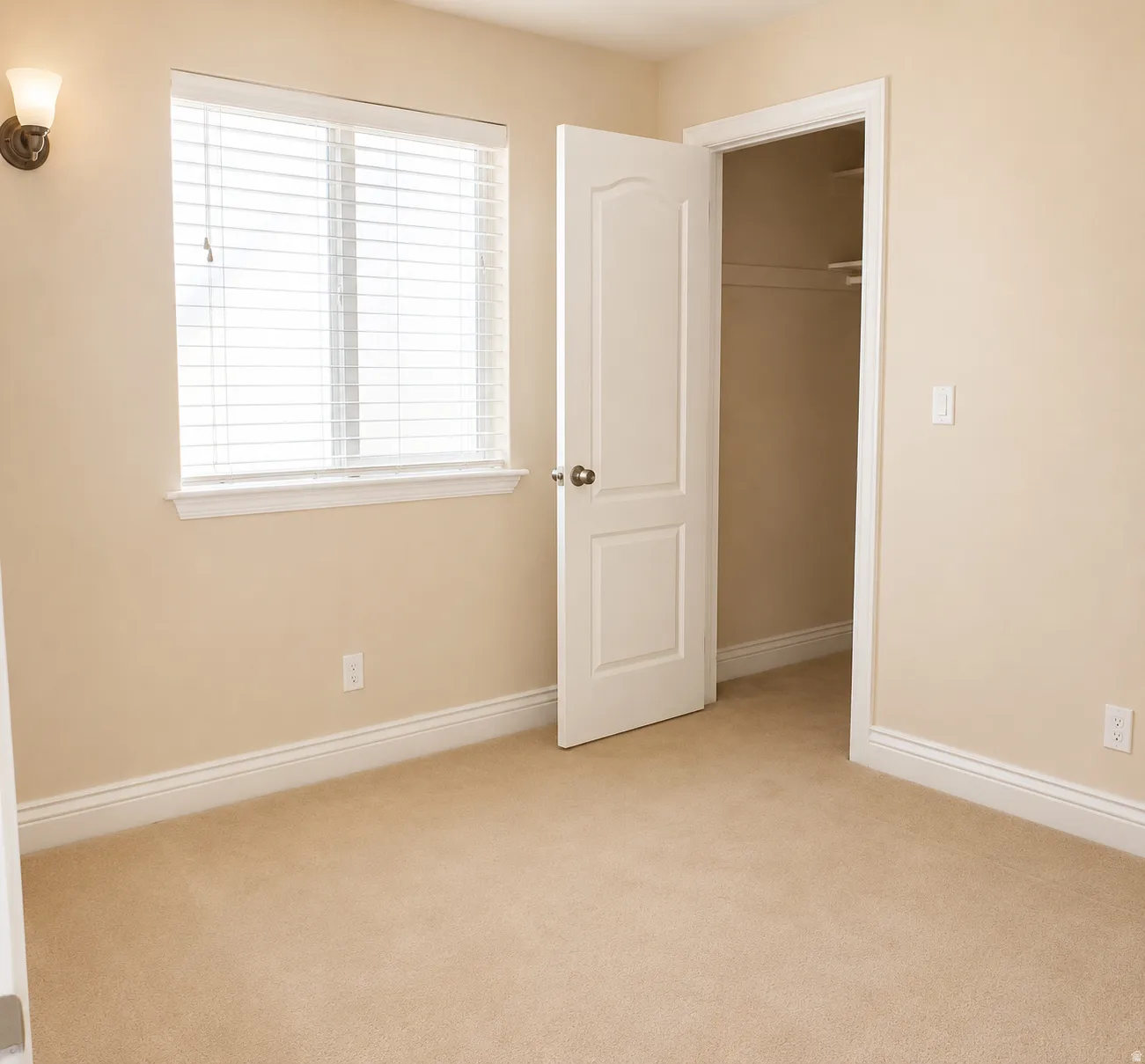 ADU #2 - Carpeted room featuring a double-pane window with blinds, a built-in closet with shelving, a wall sconce, and white baseboards