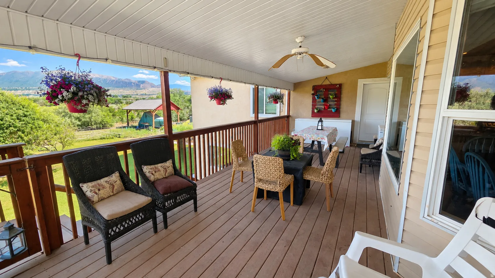 Expansive covered deck featuring wood-finish flooring, a ceiling fan, and a wood railing with metal balusters