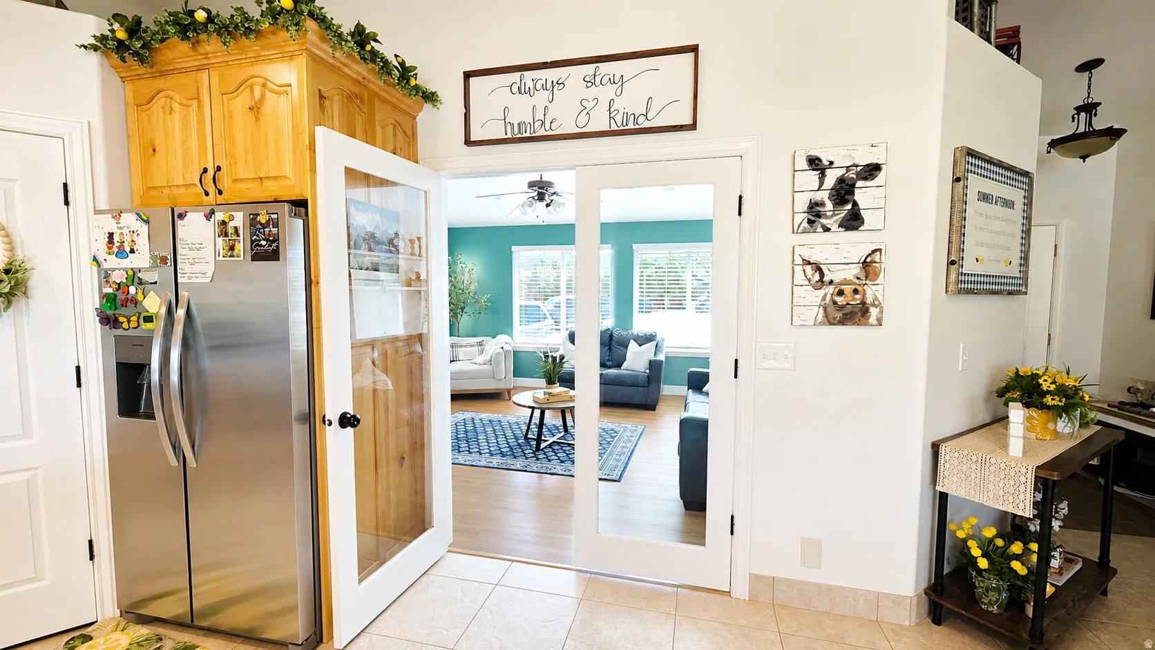 Tile flooring with French doors opening to a living area featuring wood-finish flooring and a ceiling fan