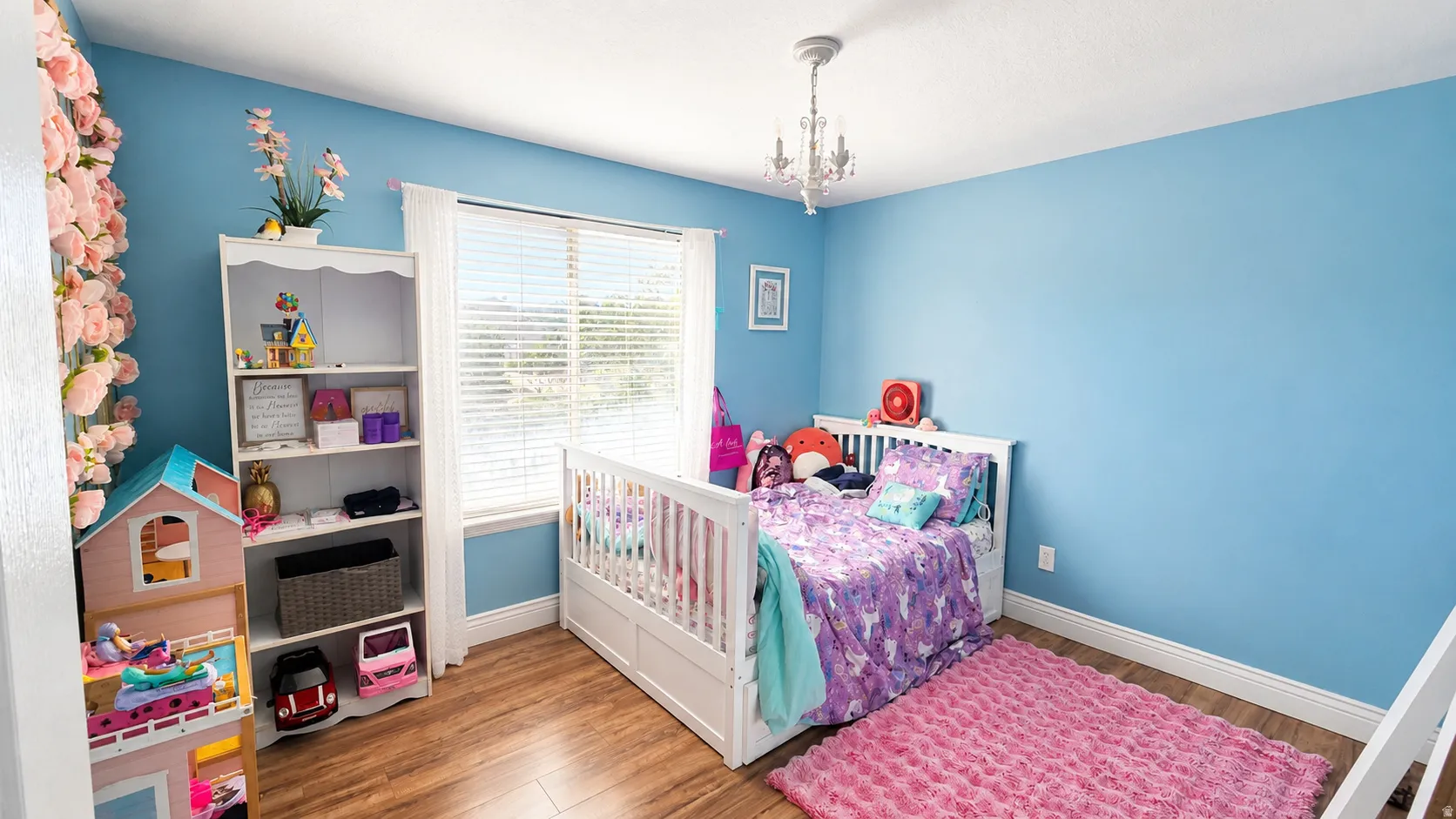 Bedroom featuring wood-finish flooring, a white trim baseboard, and a double window with horizontal blinds