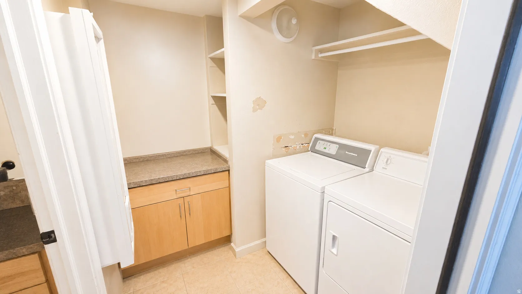 Laundry area featuring a side-by-side washer and dryer, tile flooring, built-in shelving, a wood-finish base cabinet, and a countertop