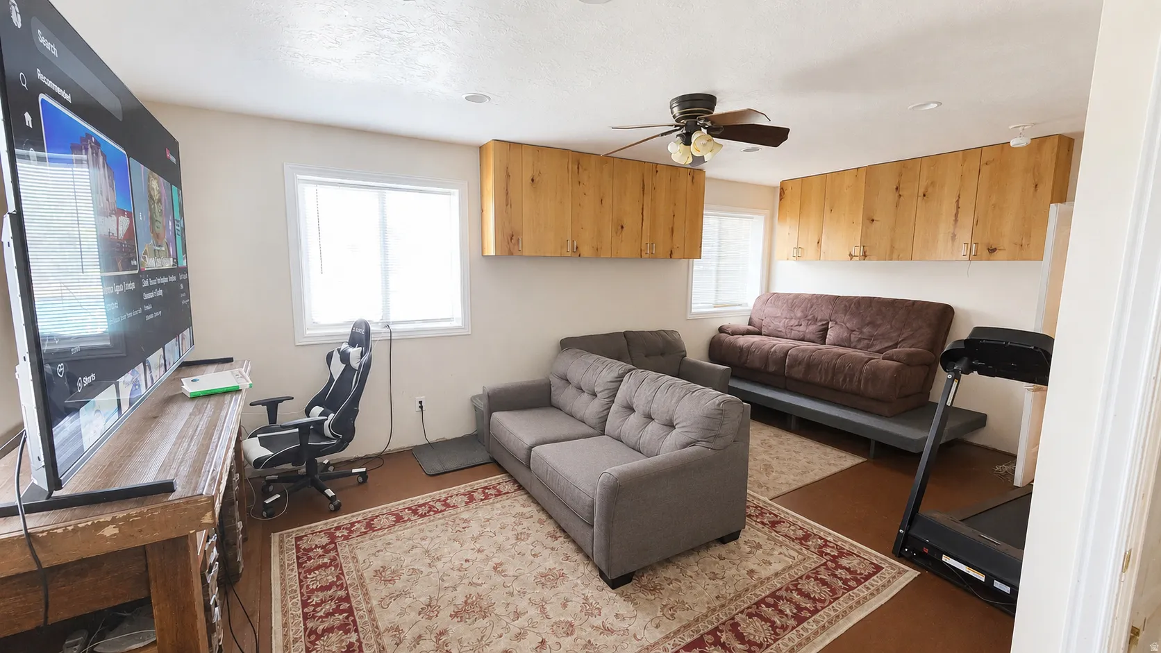 Living area featuring wood-finish flooring, a ceiling fan, recessed lighting, white trim windows, and built-in wood cabinetry