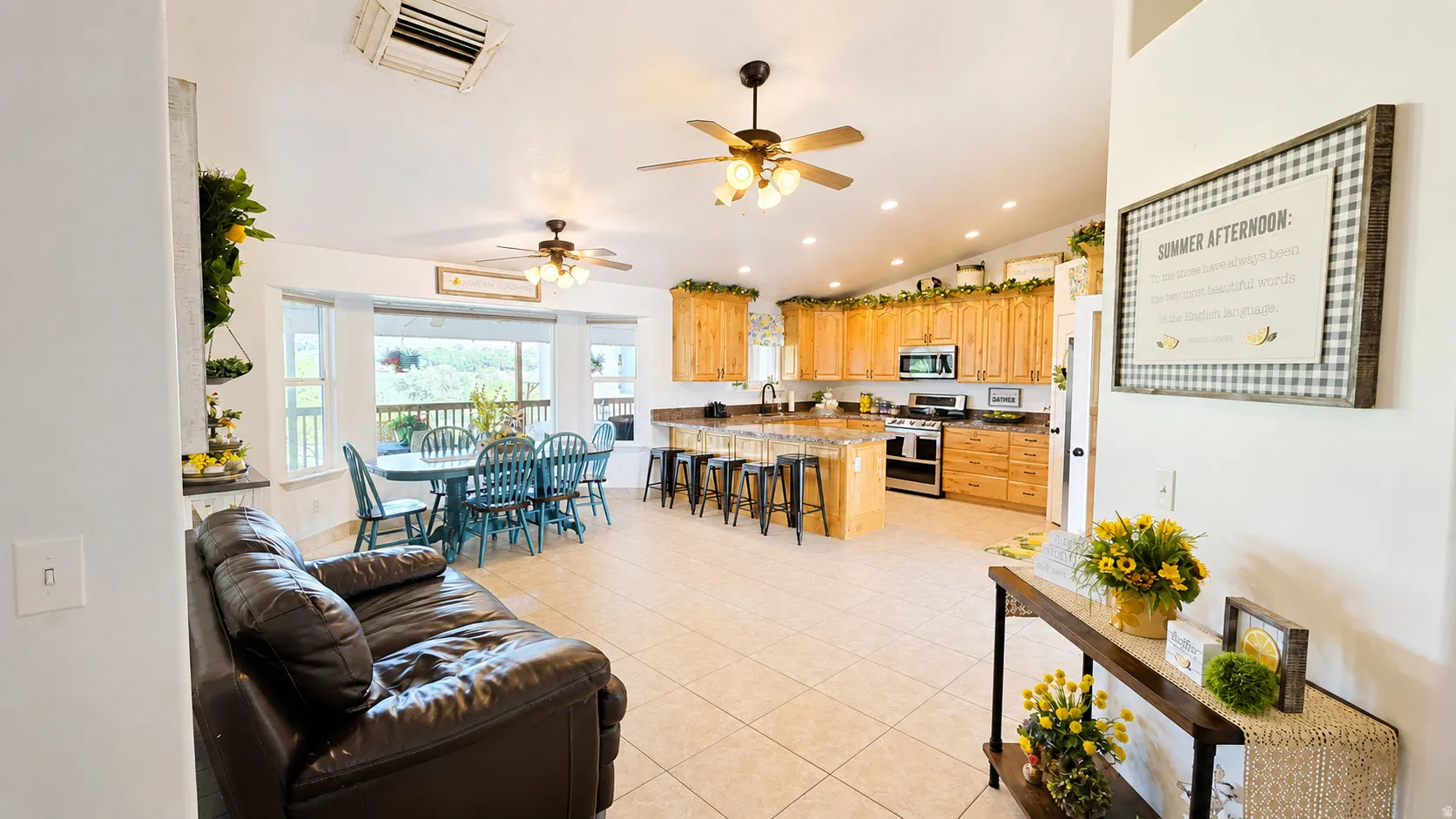 Open-concept living space featuring vaulted ceilings, tile flooring, and multiple ceiling fans