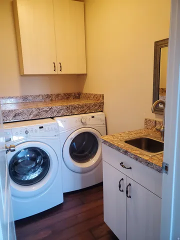 Laundry area featuring wood-finish flooring, light-toned walls, and a utility sink