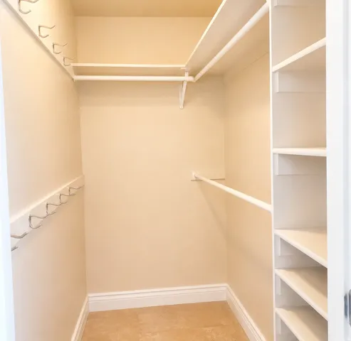 ADU #2 - Walk-in closet featuring built-in shelving, multiple hanging rods, and wall-mounted hooks