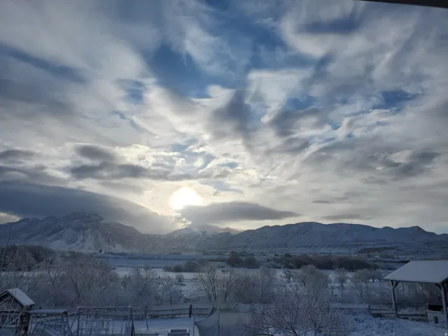Snow-covered mountain range framing a winter landscape under a bright sky