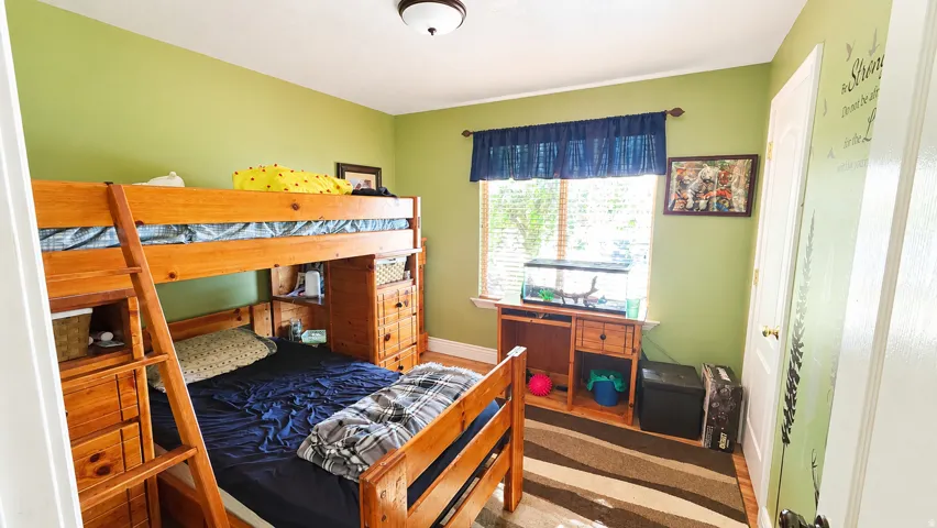 Bright room featuring a window with blinds, light green walls, a ceiling-mounted light fixture, and wood-finish flooring
