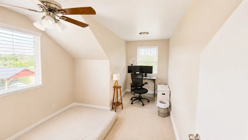 ADU #2 - Carpeted room featuring a ceiling fan with integrated lighting, a window with horizontal blinds, and sloped ceiling details