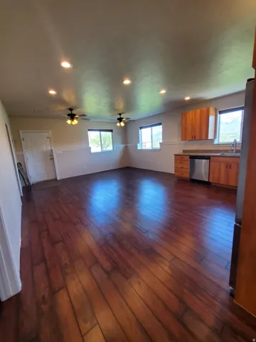 Spacious room featuring wood-finish flooring, recessed lighting, and two ceiling fans