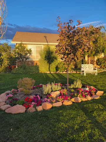 Manicured lawn with a stone-edged flower bed featuring colorful plantings