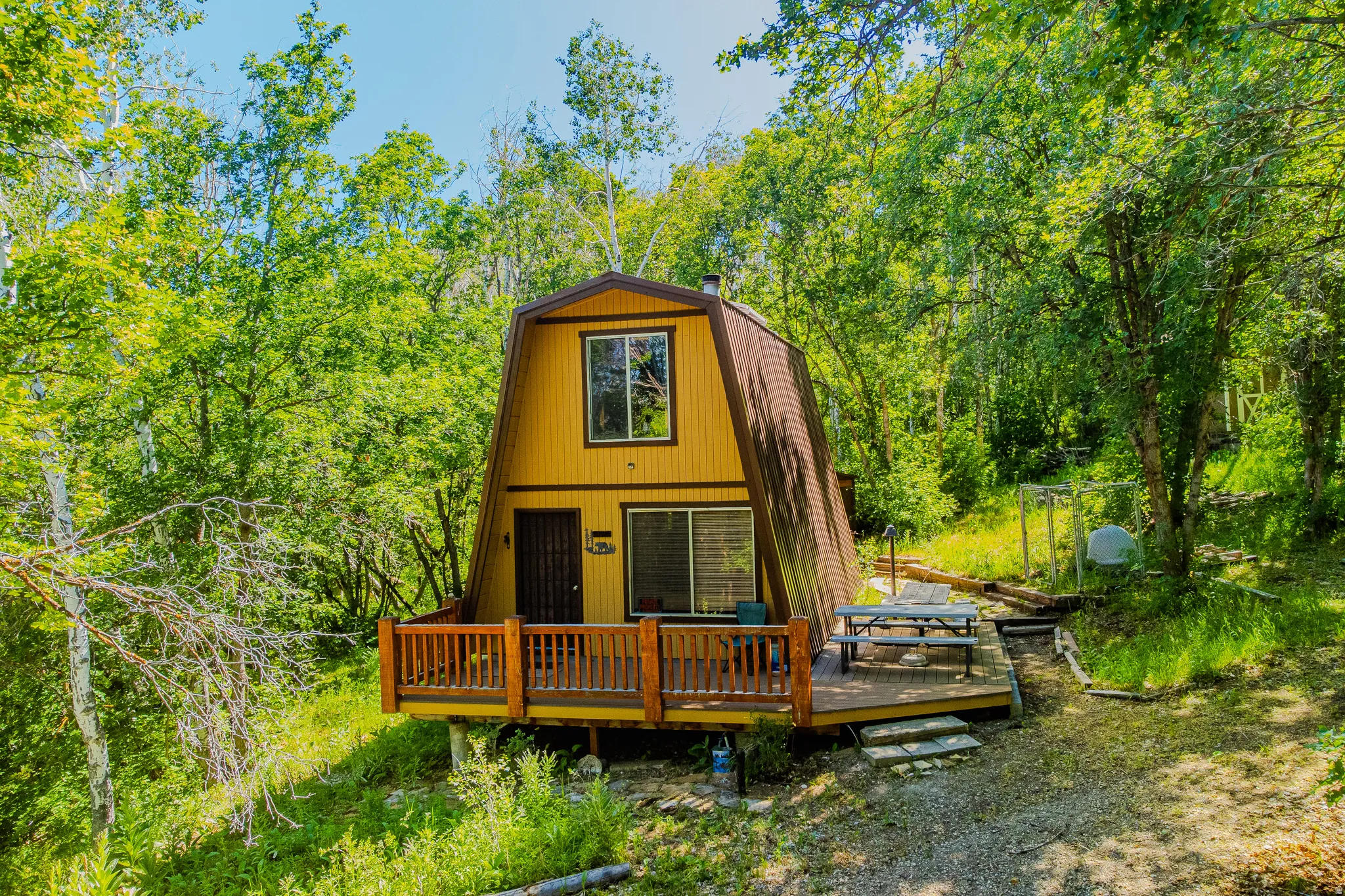 A-frame structure with a contrasting roofline, featuring a ground-level deck with wooden railing