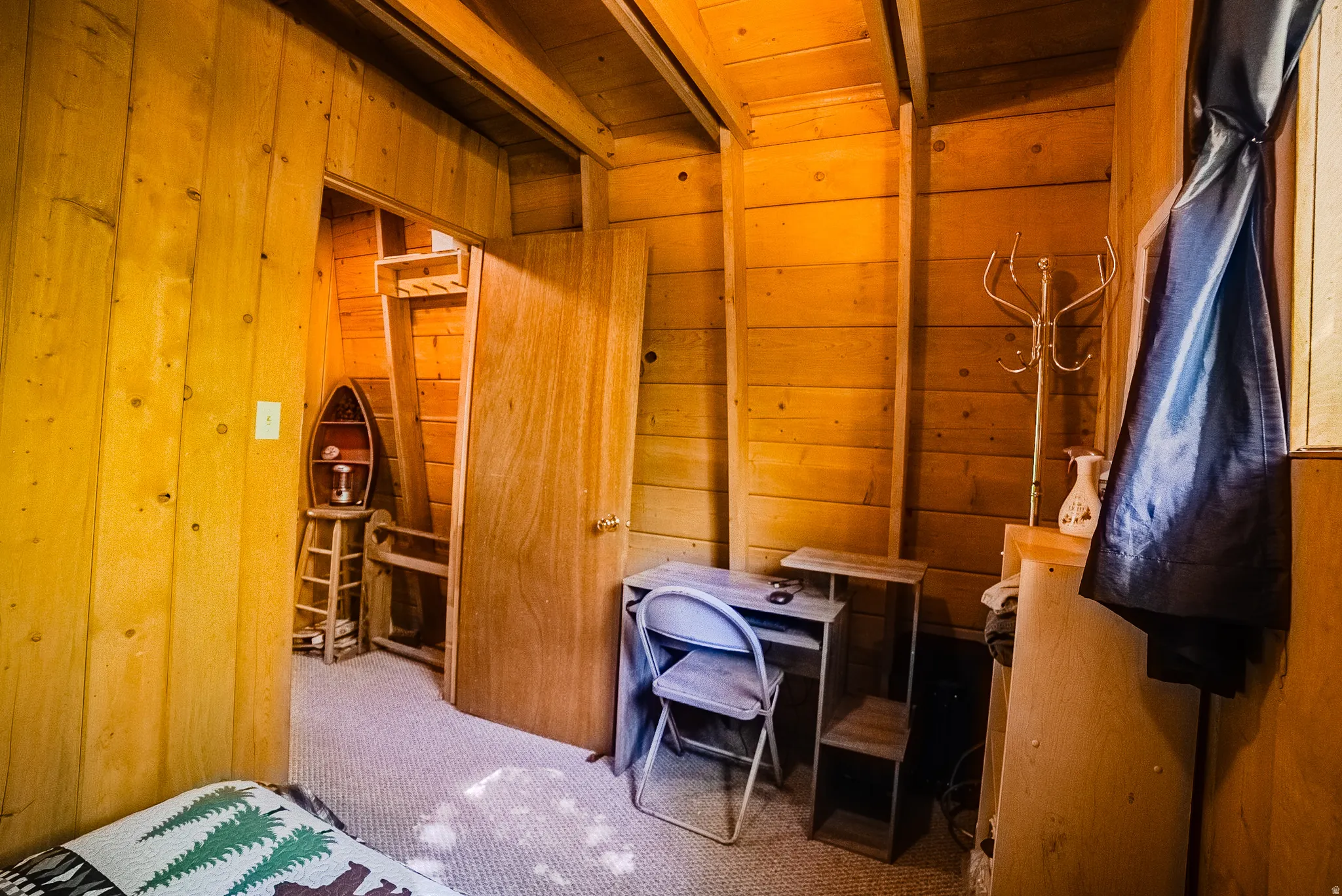 Wood-paneled interior room featuring exposed ceiling beams and a neutral carpet