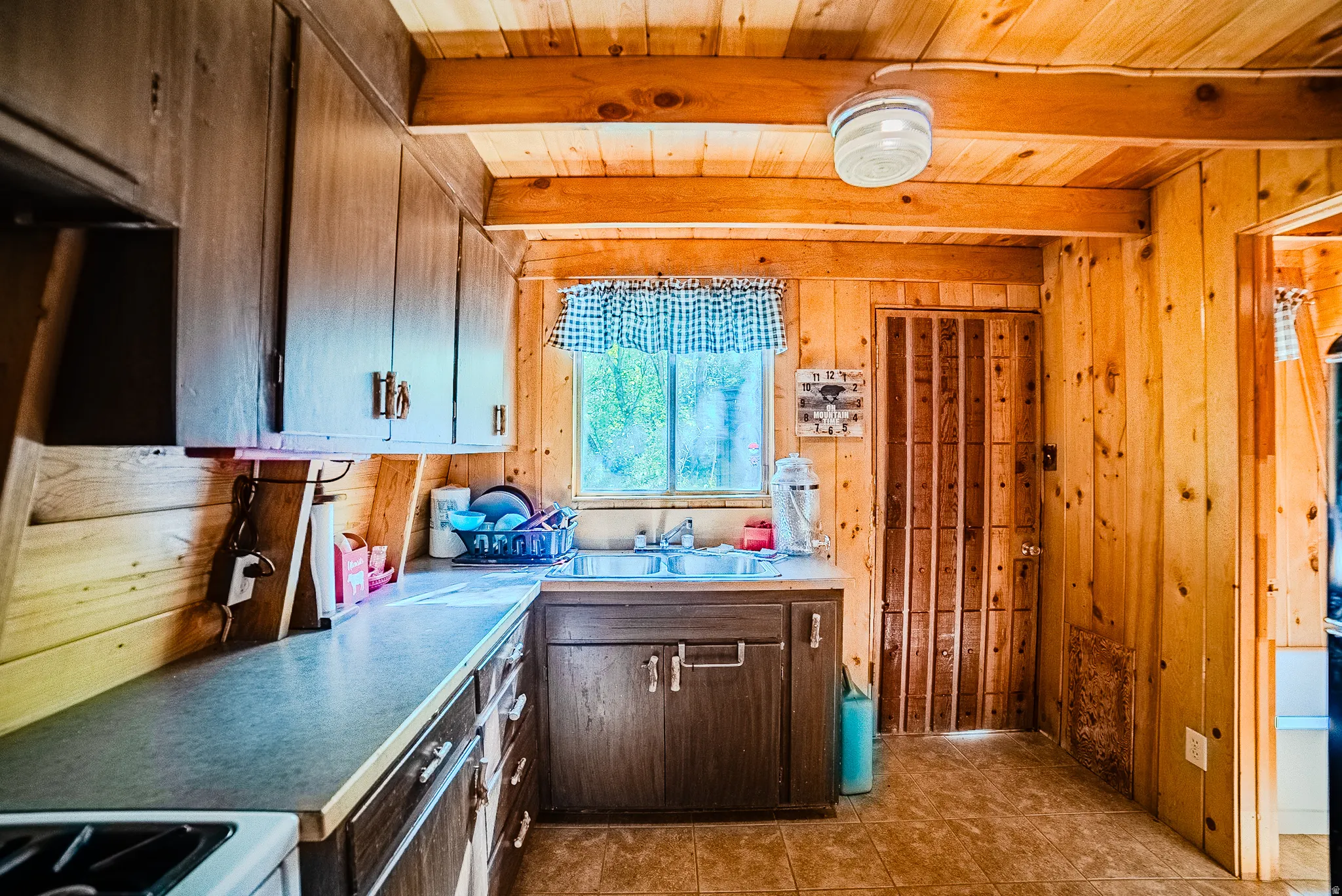 Kitchen featuring wood-paneled walls and ceiling with exposed beams