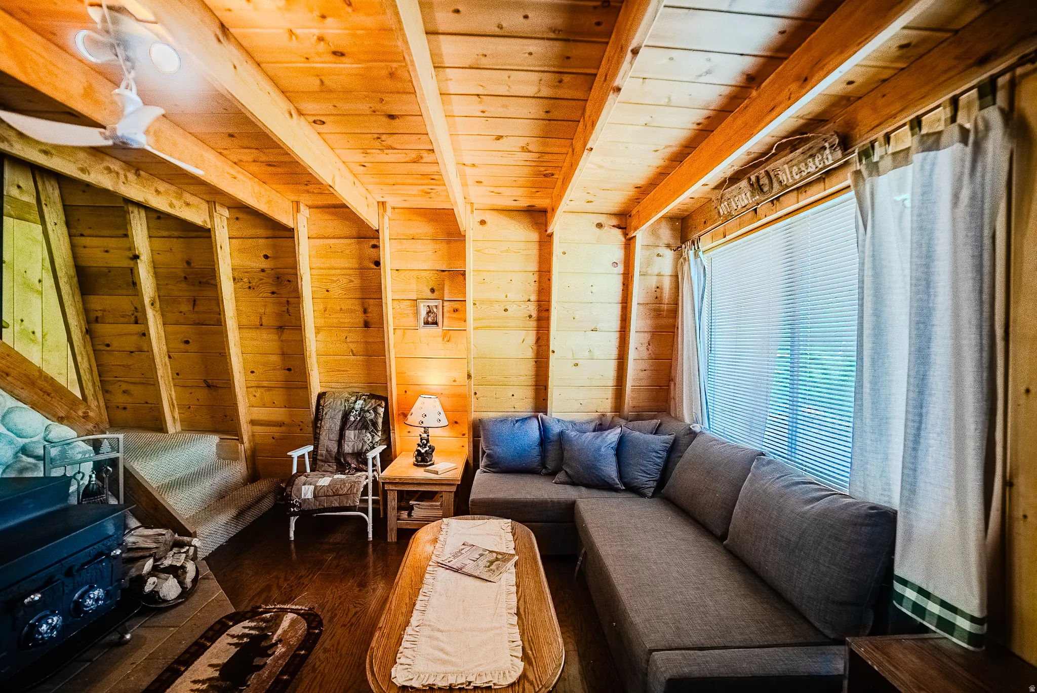 Living area featuring wood-paneled walls, exposed wood beam ceiling, and wood-finish flooring