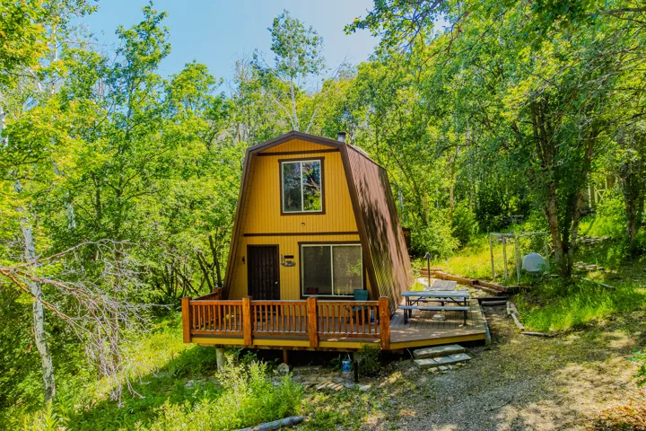 A-frame structure with a contrasting roofline, featuring a ground-level deck with wooden railing