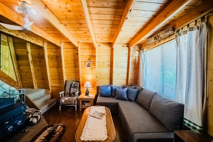 Living area featuring wood-paneled walls, exposed wood beam ceiling, and wood-finish flooring