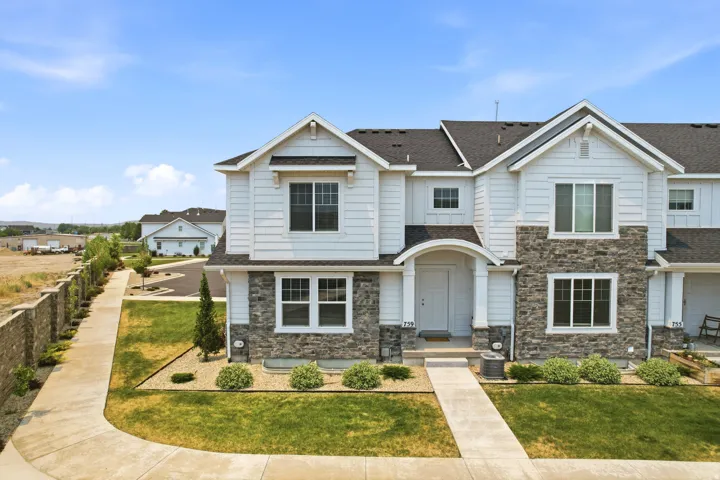 Contemporary townhouse exterior featuring white siding and stone accents