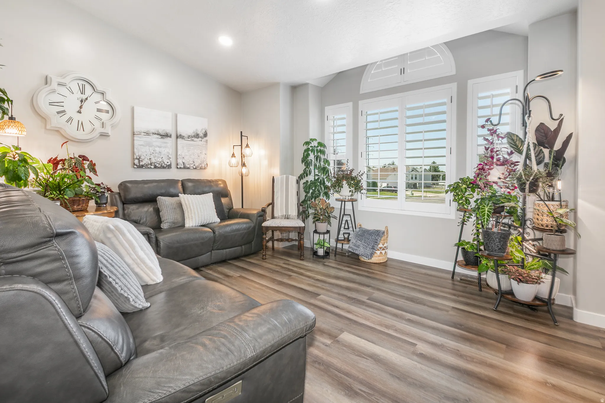 Spacious living area featuring wood-finish flooring, recessed lighting, and large windows with plantation shutters