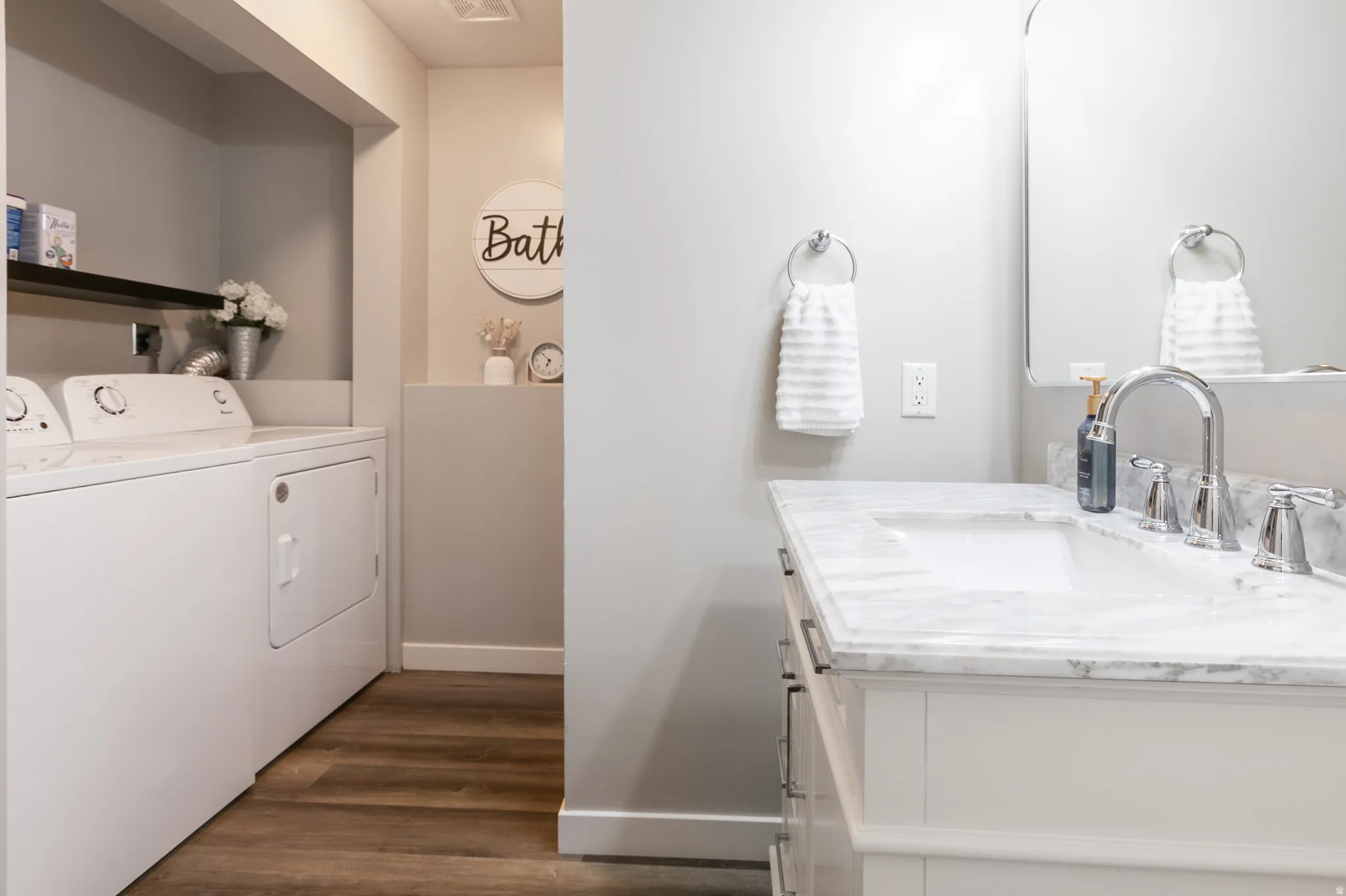 Bathroom vanity featuring a polished chrome faucet, under-mount sink, and a white countertop with grey veining