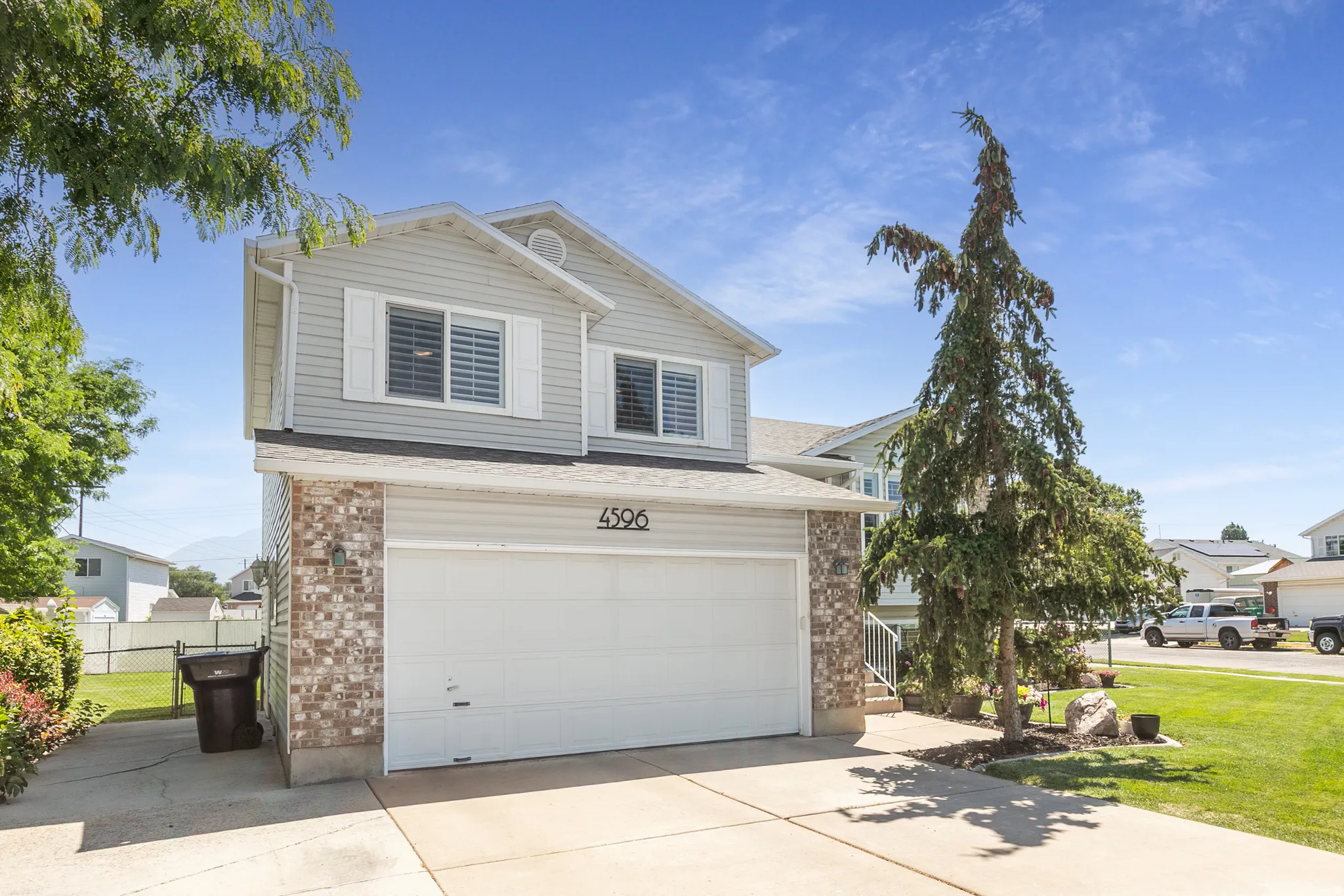 Two-story residence featuring light gray siding with brick-finish accenting