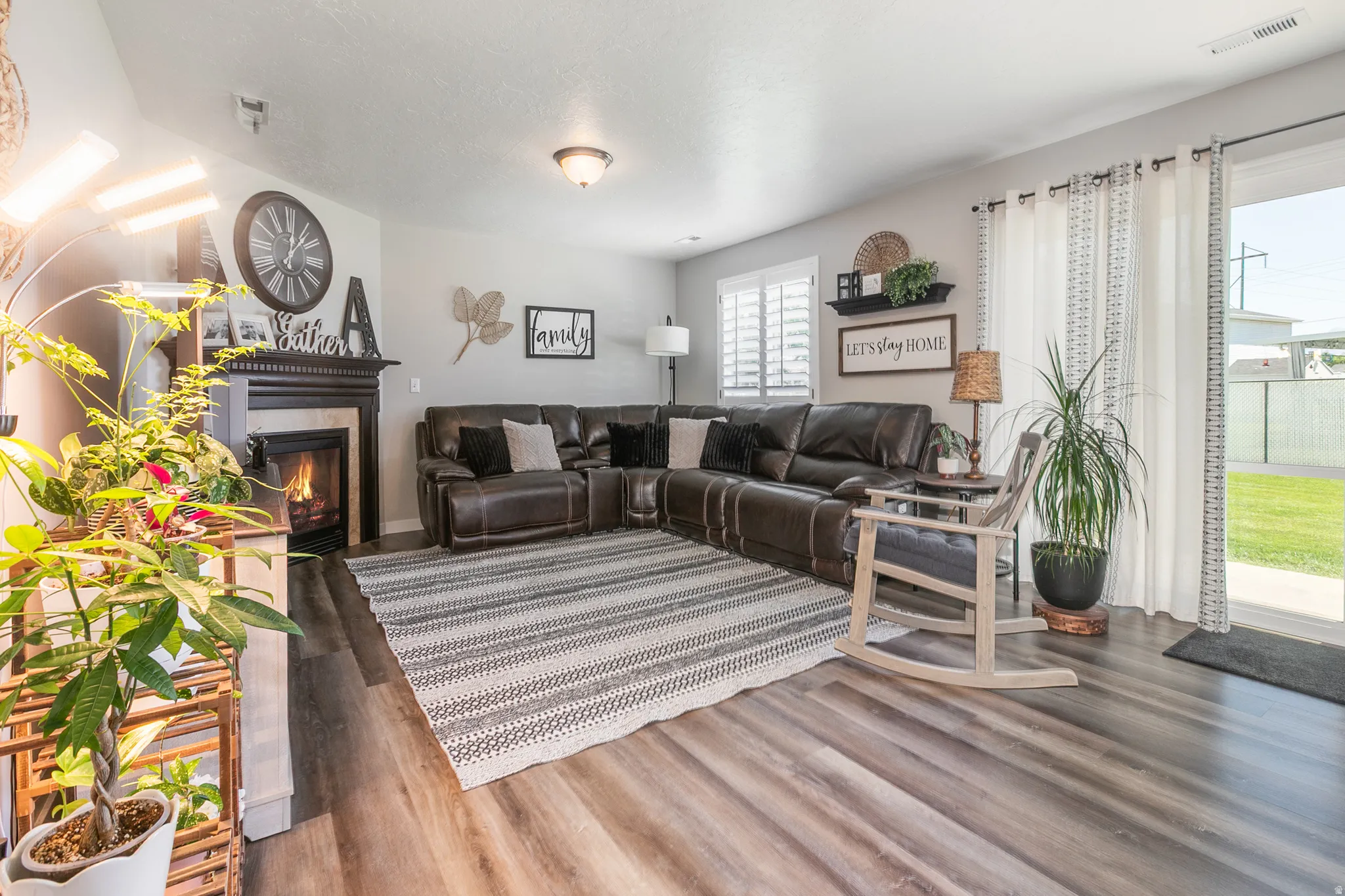 Spacious living area featuring wood-finish flooring, a built-in fireplace with a dark wood mantel, and sliding glass doors