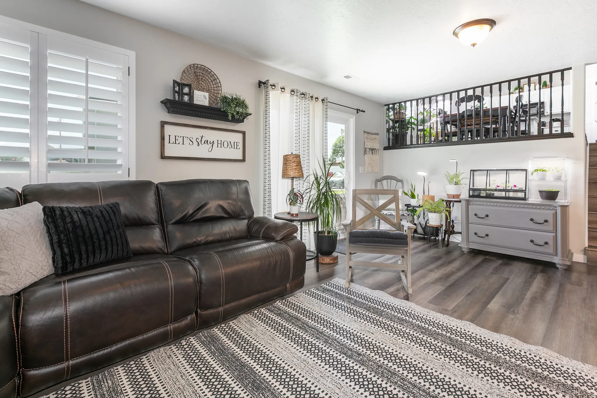 Spacious living area featuring wood-finish flooring, white plantation shutters, and a white ceiling with a flush-mount light fixture