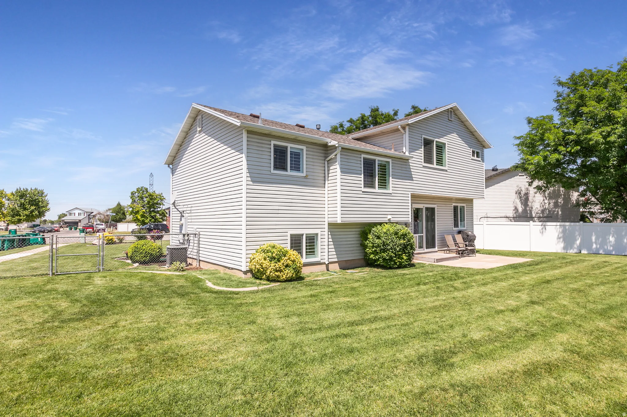 Spacious backyard featuring an expansive lawn, concrete patio, and mature landscaping